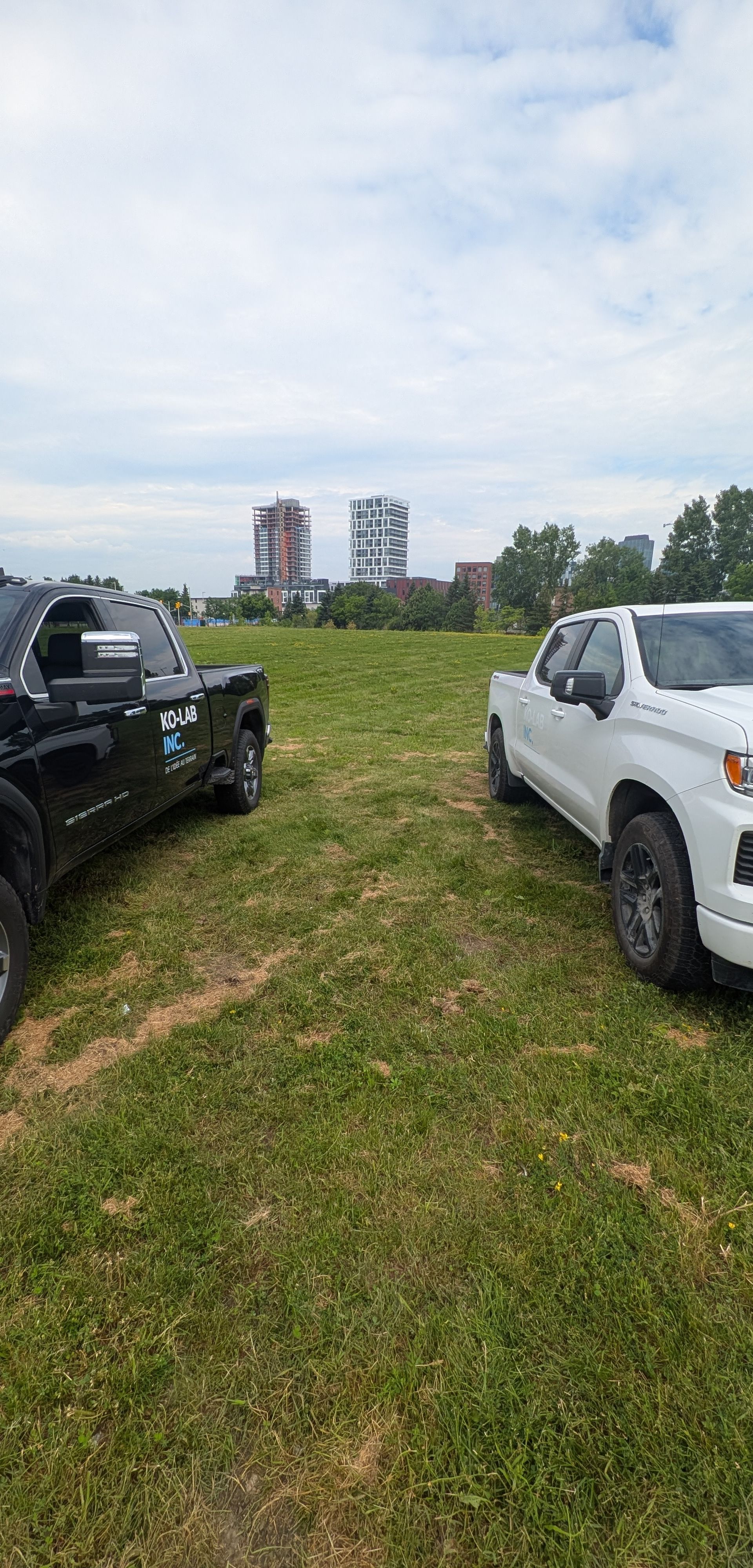 Deux pick-up KO-LAB stationnés sur un terrain gazonné, immeubles en arrière-plan