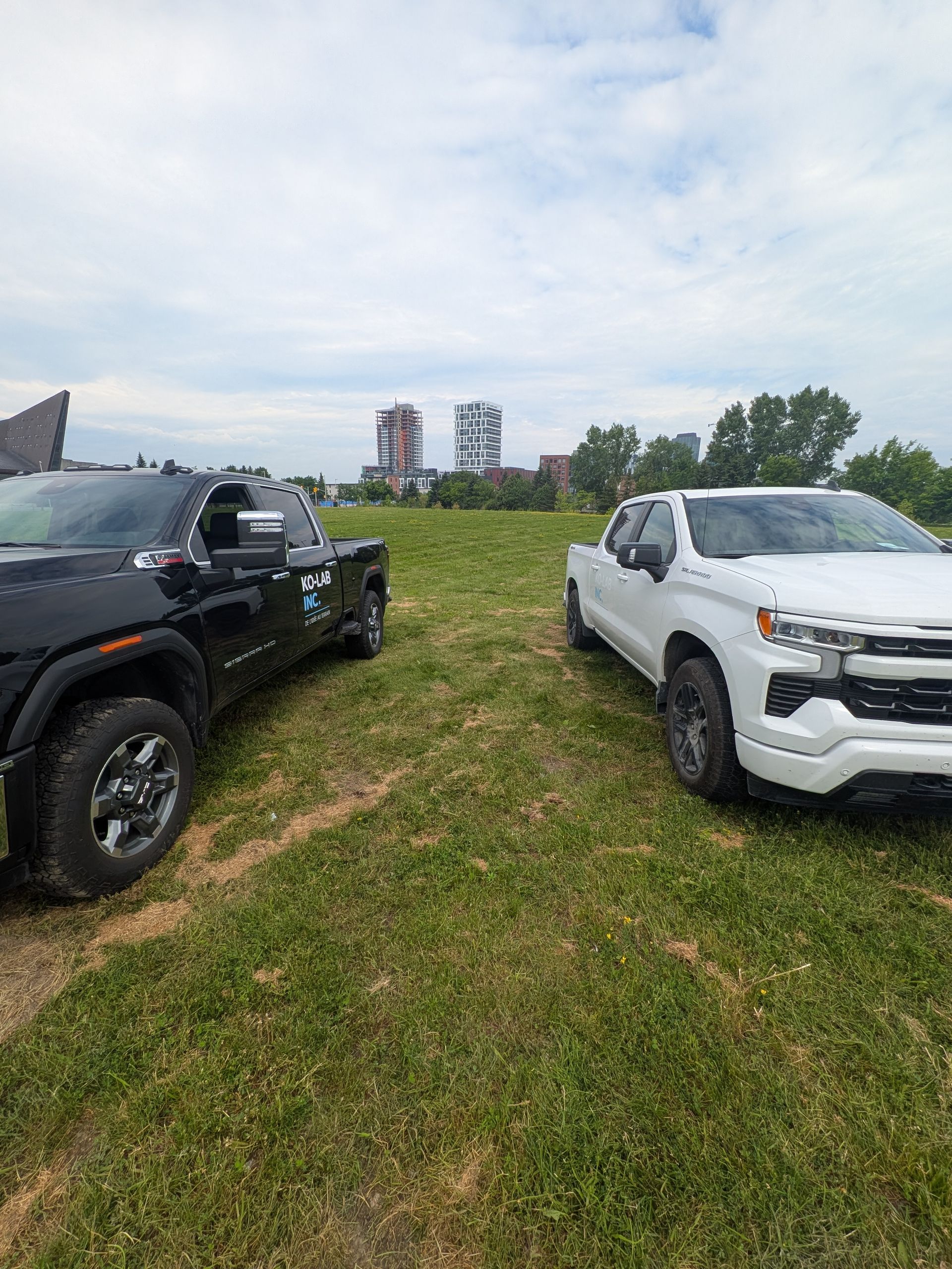 Deux pick-up KO-LAB stationnés sur un terrain gazonné, immeubles en arrière-plan