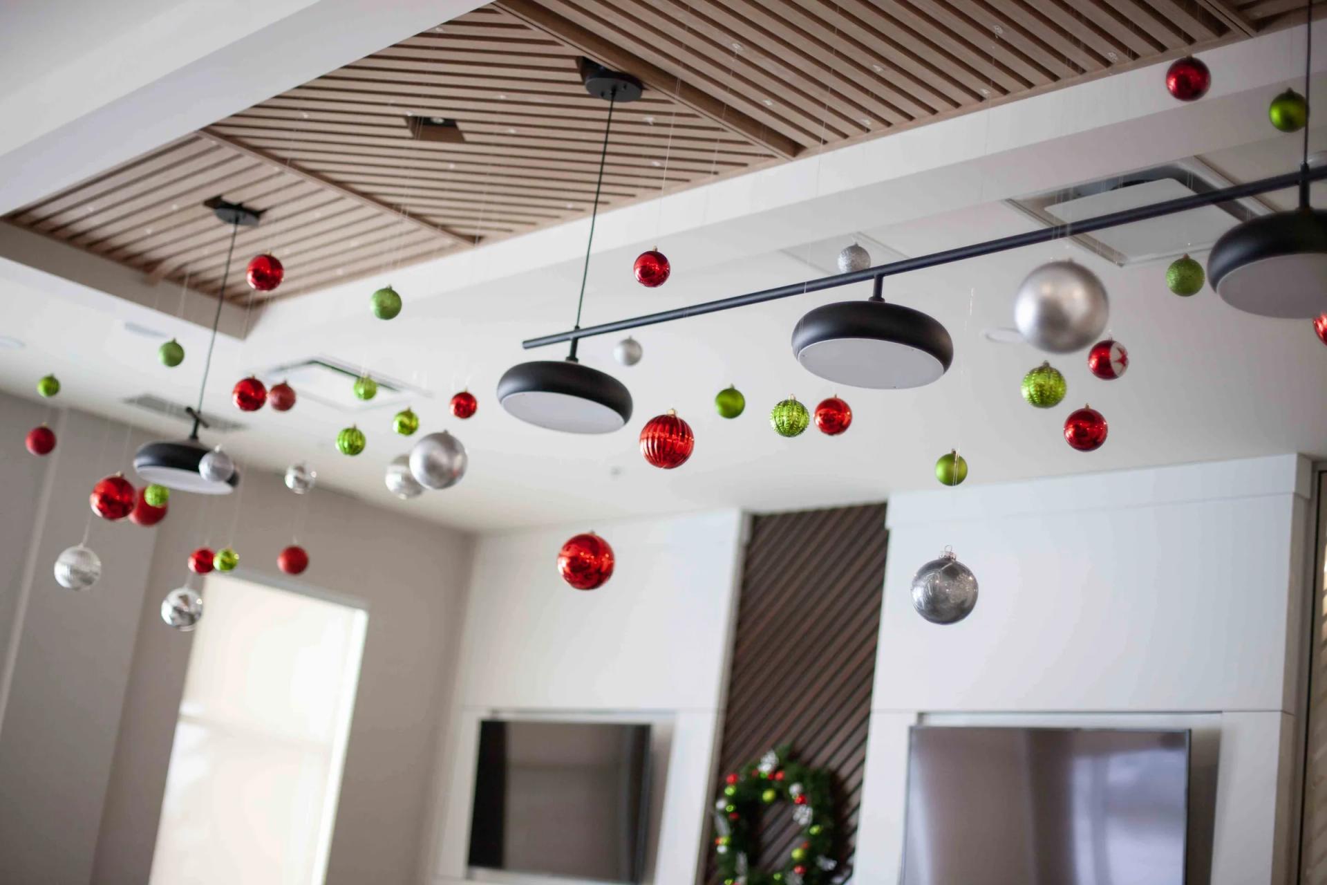 Boules de Noël rouges, vertes et argentées suspendues au plafond d’un espace commercial