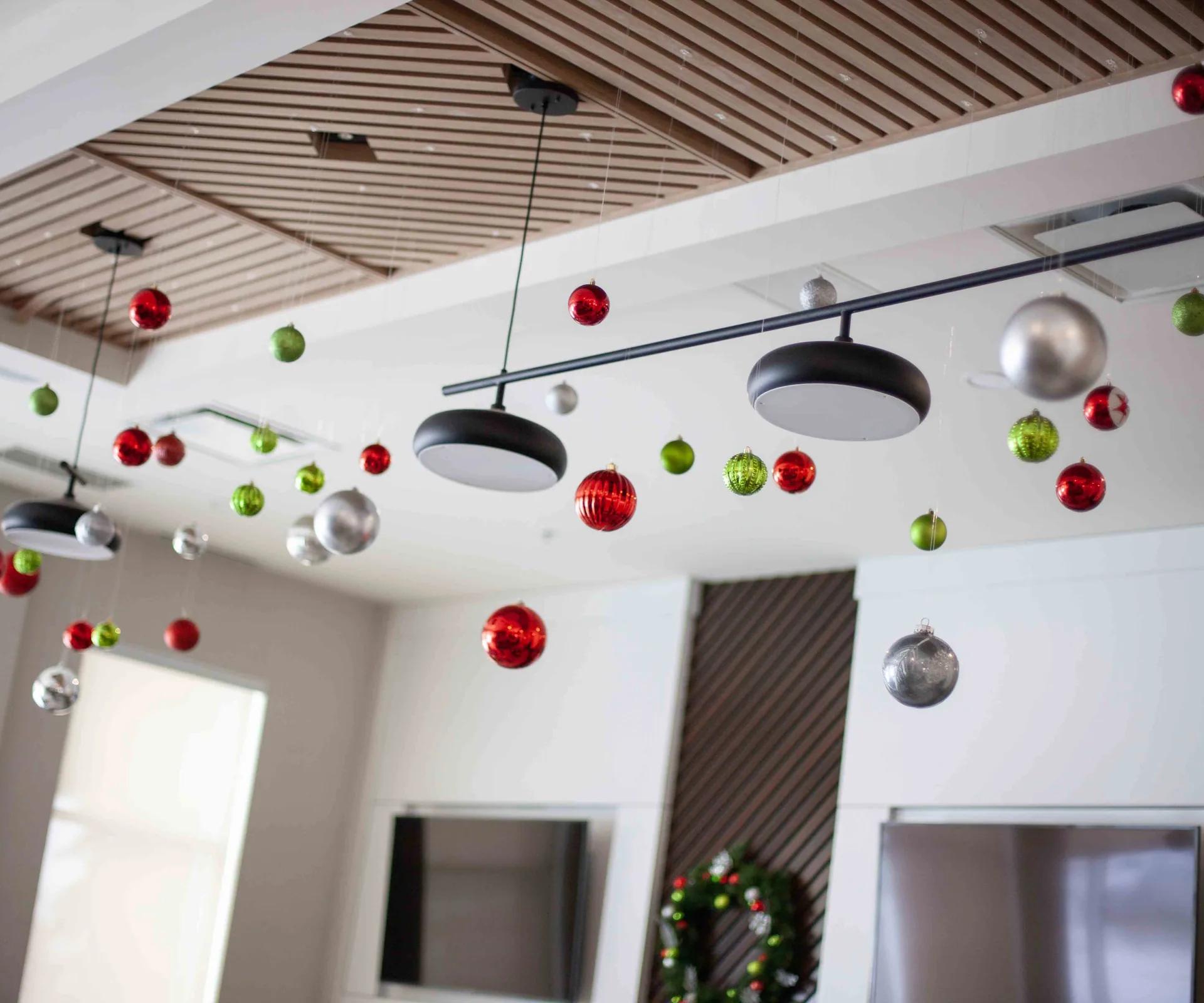 Boules de Noël rouges, vertes et argentées suspendues au plafond d’un espace commercial