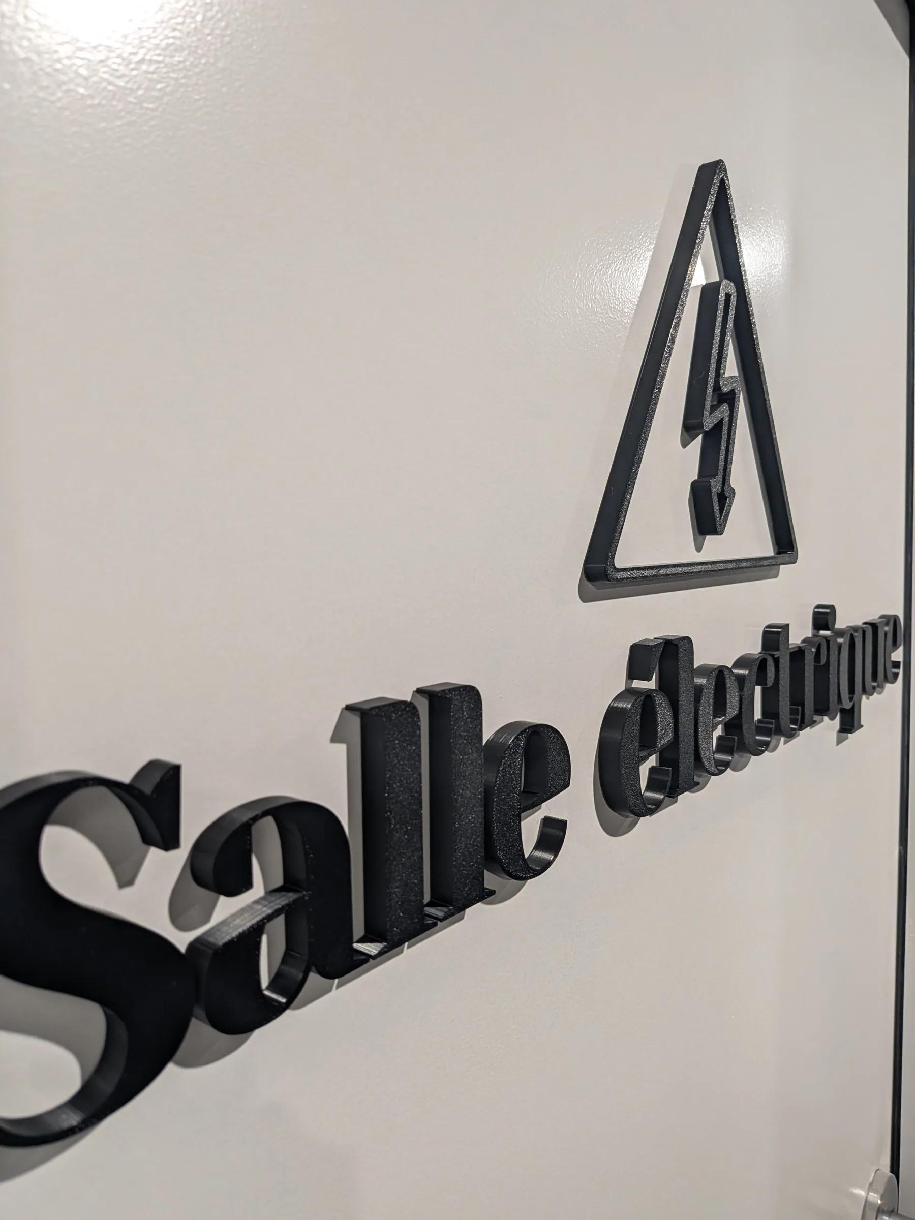 Pictogramme et lettrage 3D « Salle électrique » fabriqués au LAB, posés sur un mur blanc