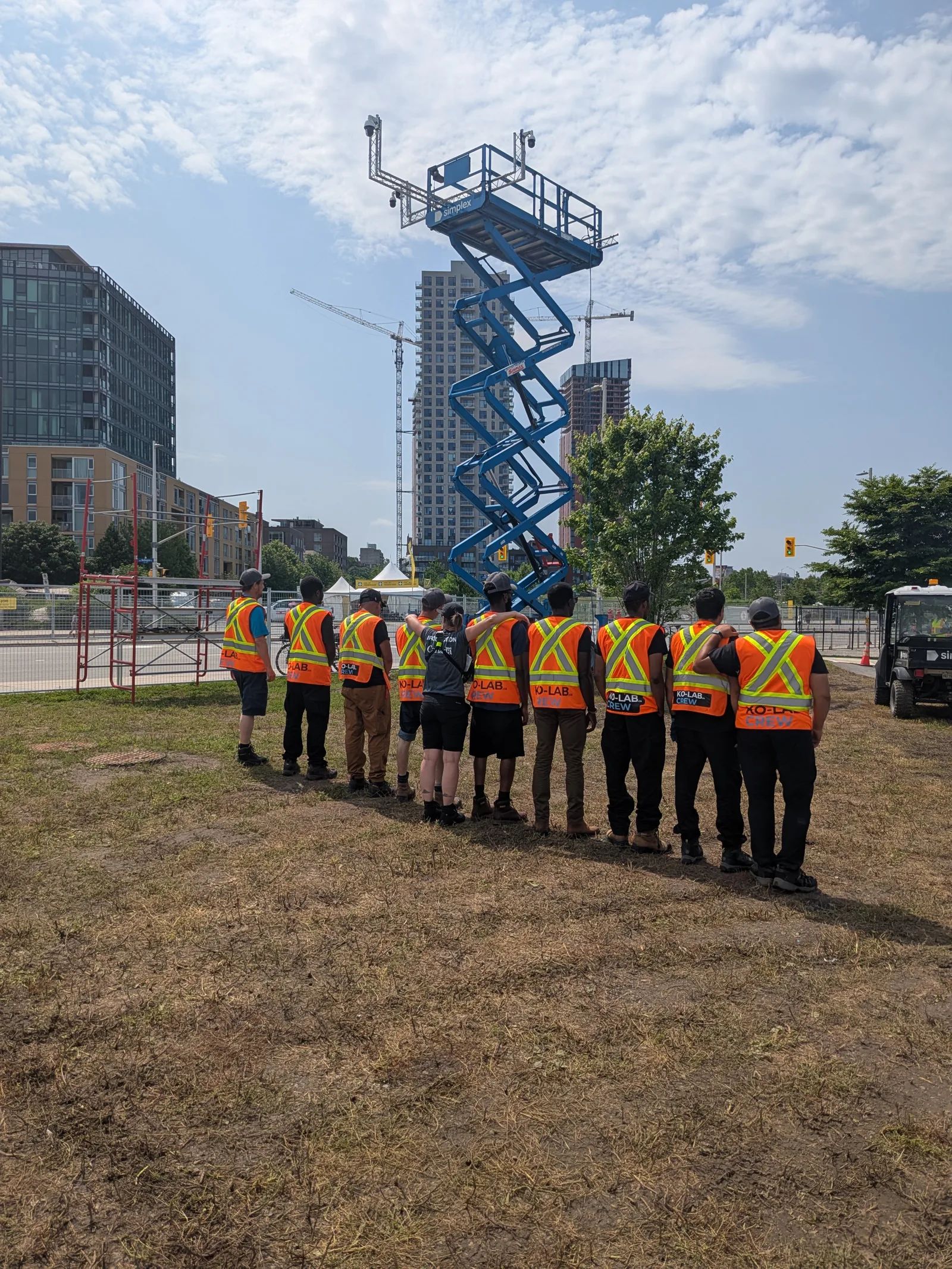 Équipe KO-LAB en gilets de sécurité devant une nacelle à ciseaux, sur un site événementiel