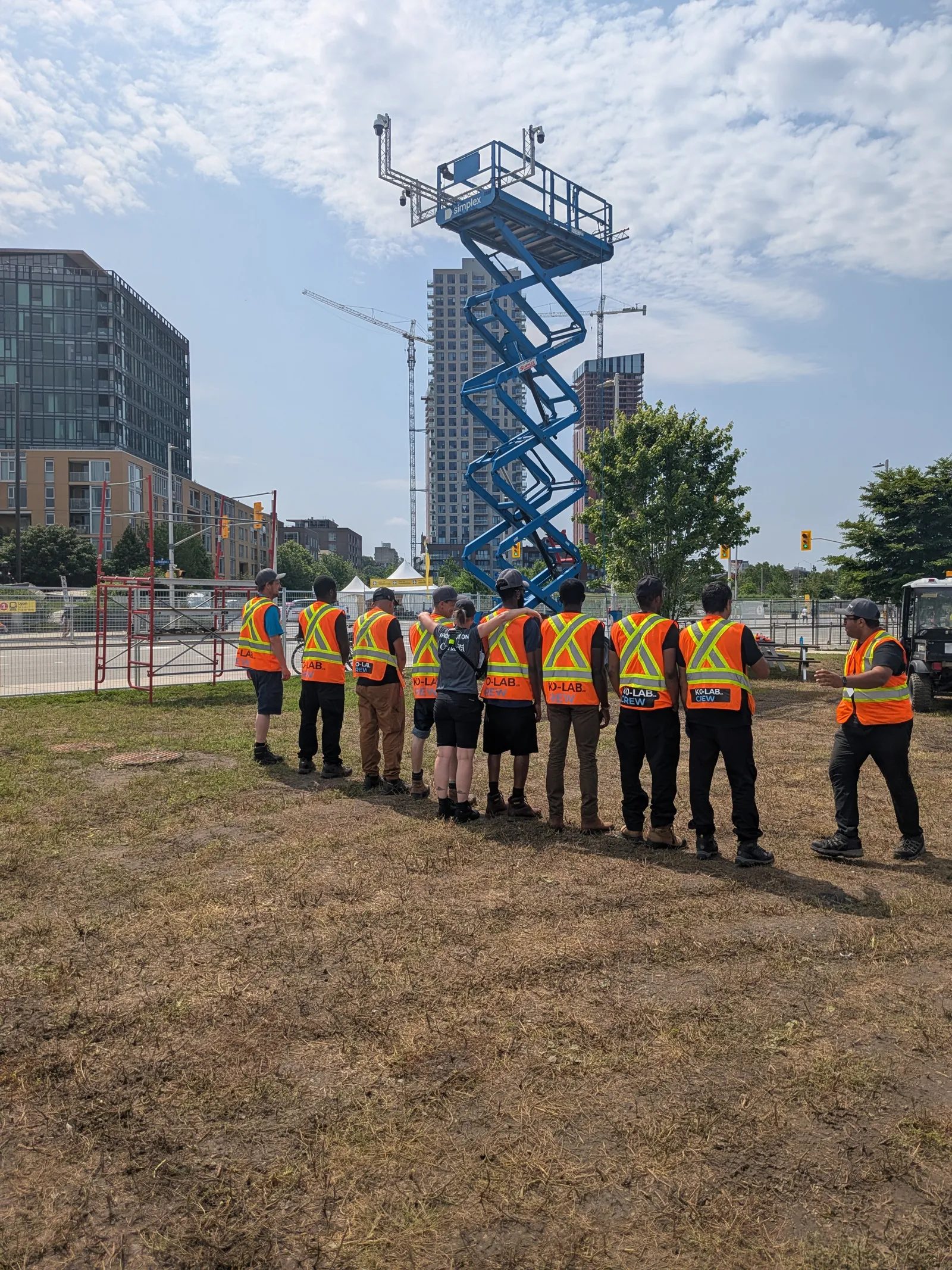 Équipe KO-LAB en gilets de sécurité sur un site en ville, nacelle à ciseaux en arrière-plan