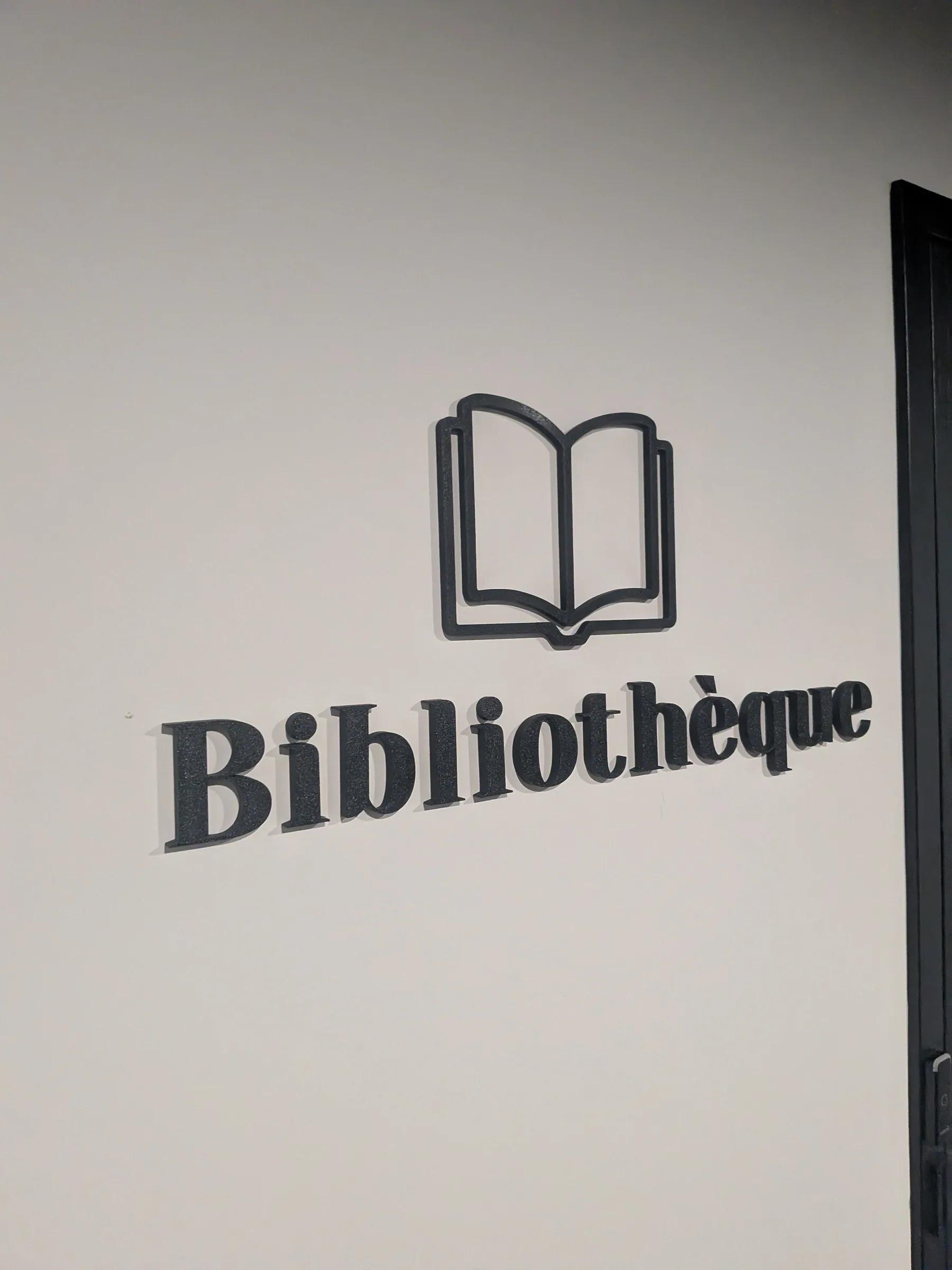 Pictogramme et lettrage 3D « Bibliothèque » sur un mur blanc