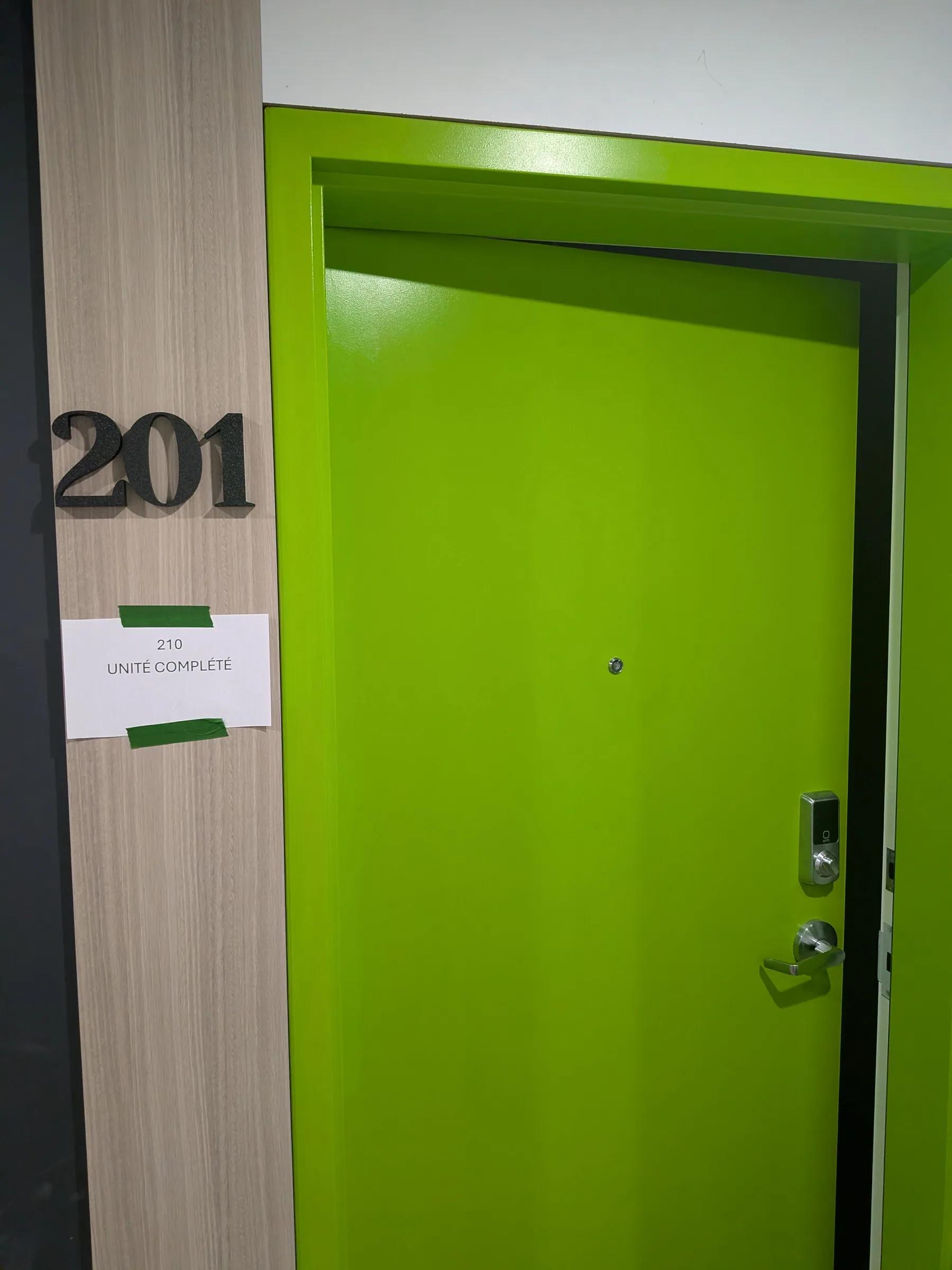 Numéro d’unité 201 en lettres 3D noires à côté d’une porte verte