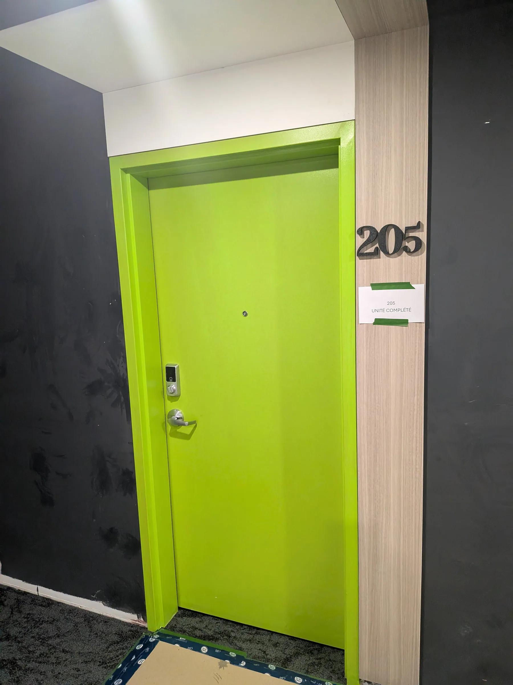 Numéro d’unité 205 en lettres 3D noires à côté d’une porte verte