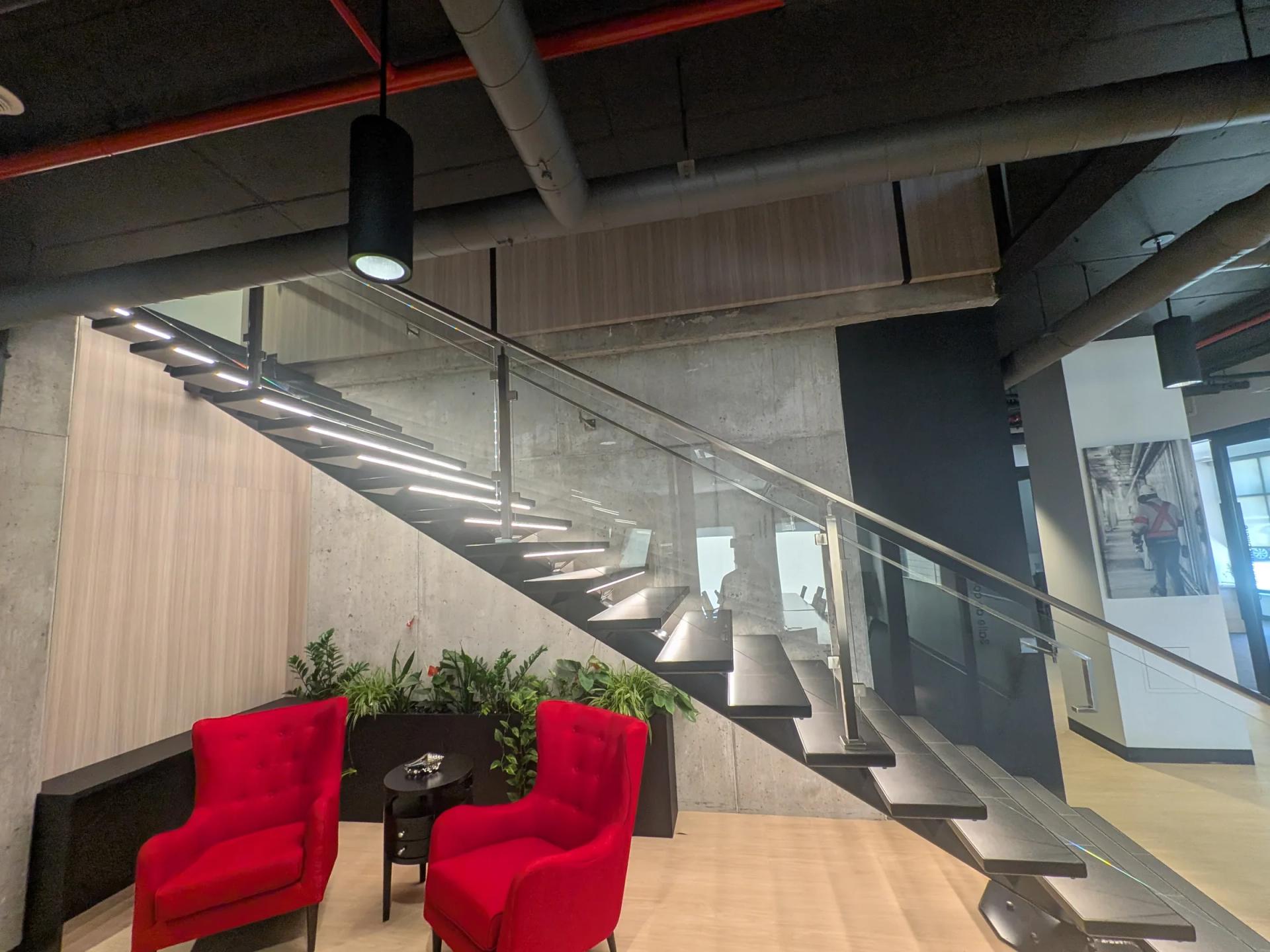 Escalier en bois et béton avec deux fauteuils rouges dans un hall