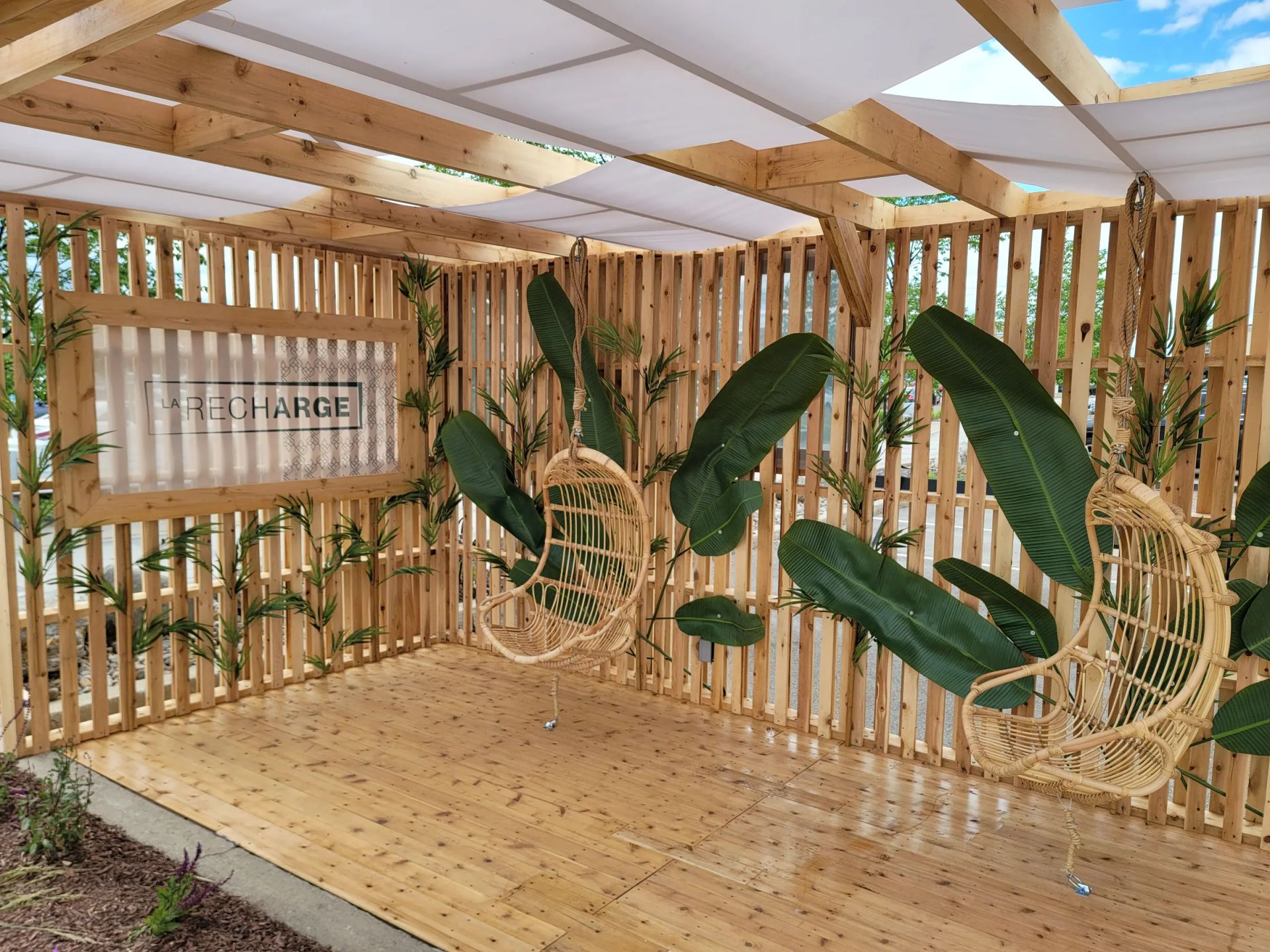 Terrasse en bois couverte, cloisons à claire-voie et fauteuils suspendus en rotin