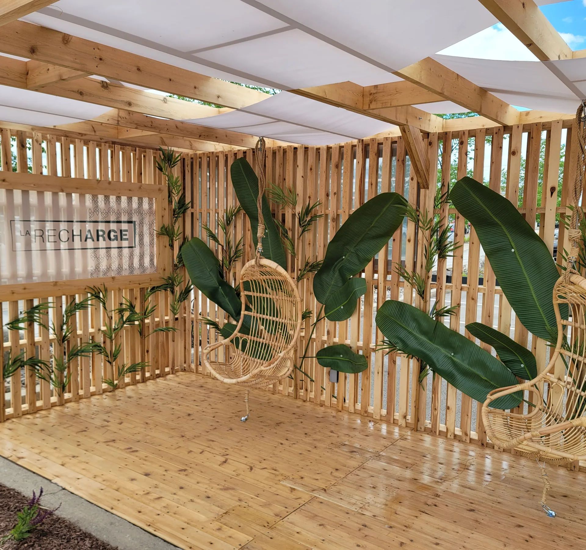 Terrasse en bois couverte, cloisons à claire-voie et fauteuils suspendus en rotin