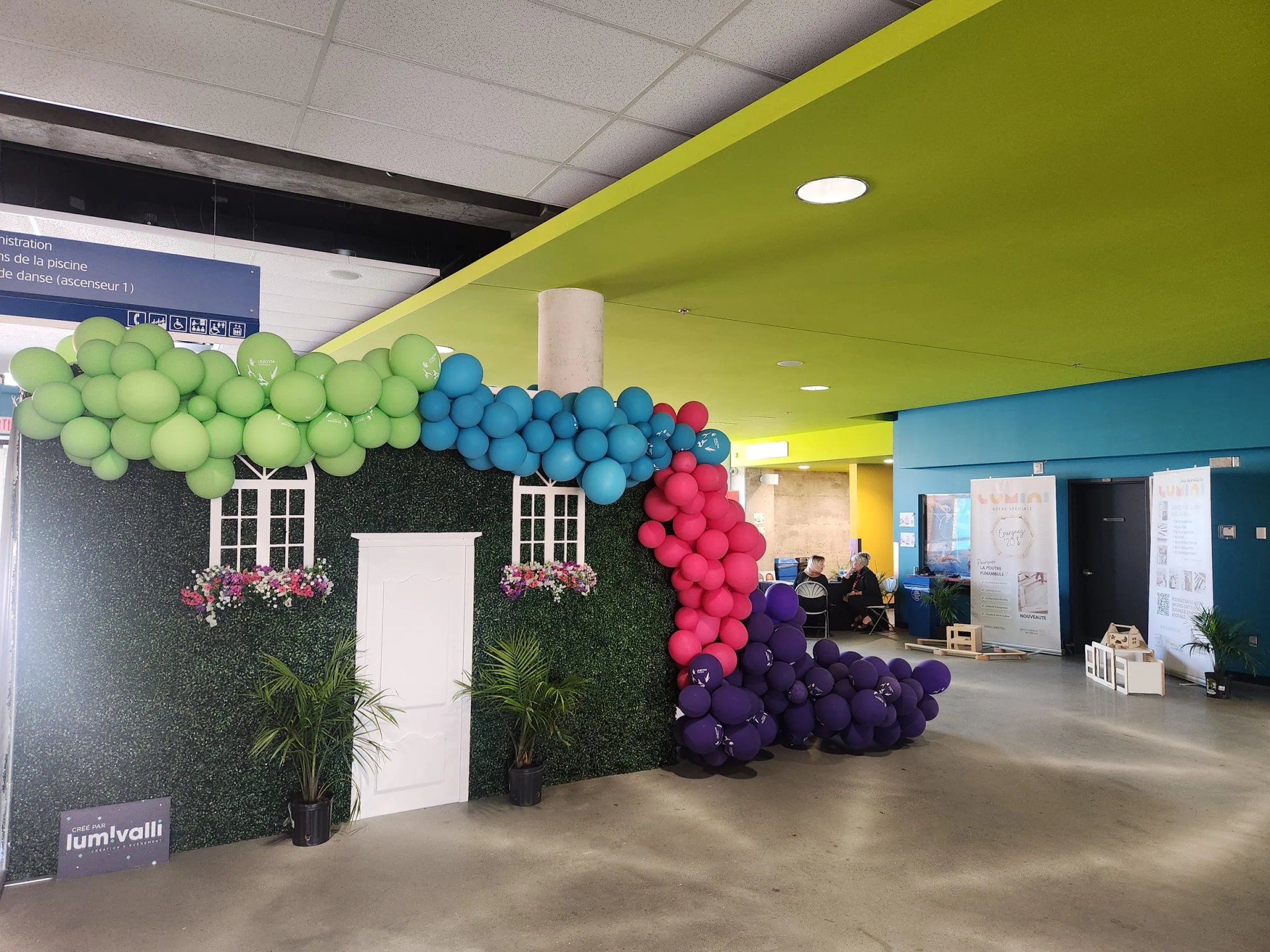 Arche de ballons multicolores autour d’une façade décorative dans un hall sportif