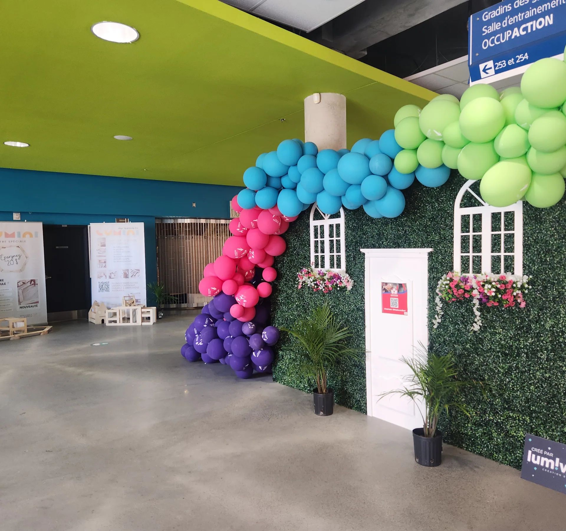 Décor de façade avec fenêtres, plantes et arche de ballons, vue rapprochée