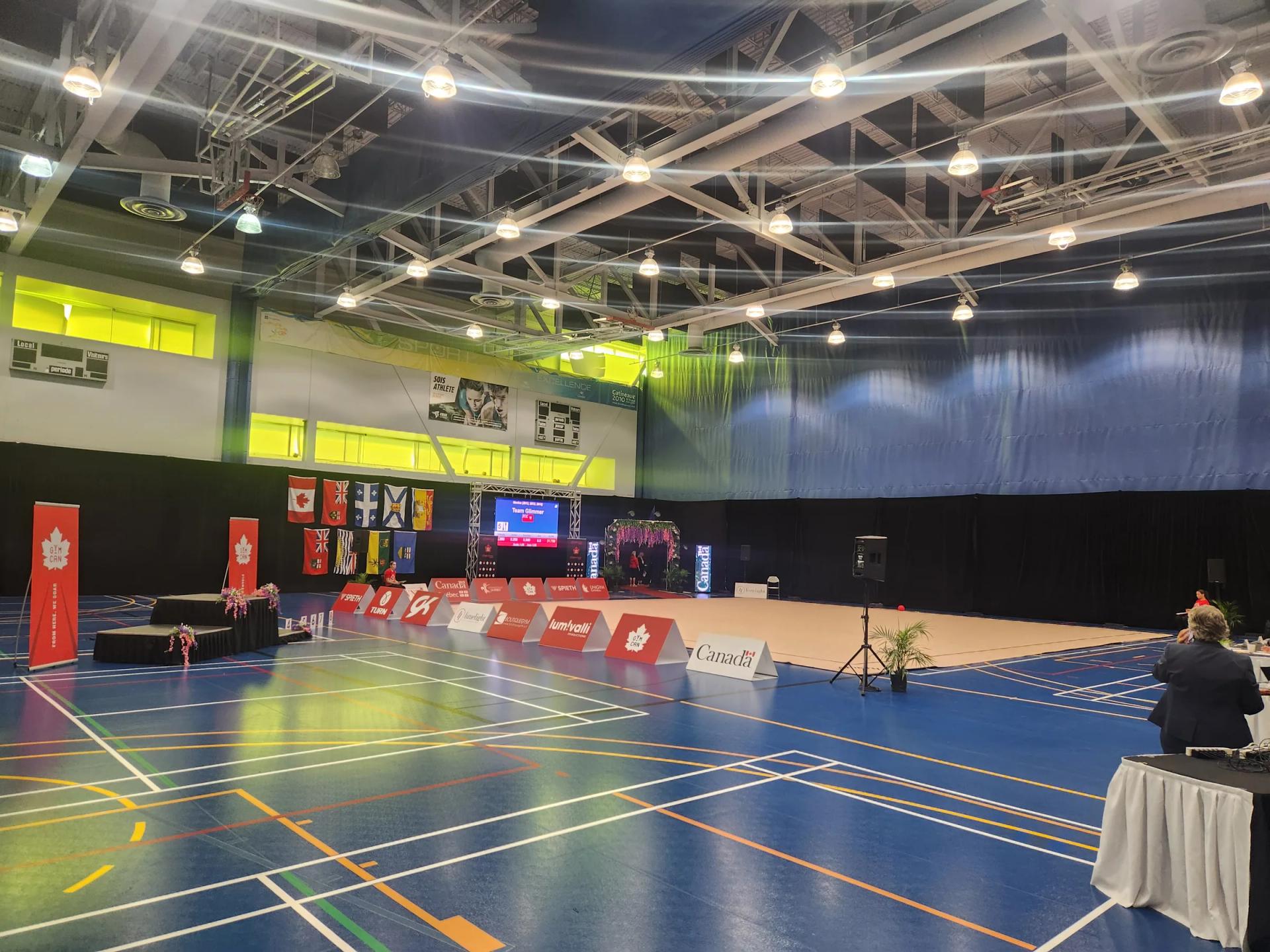 Plateau de compétition installé dans un gymnase, tables et écrans