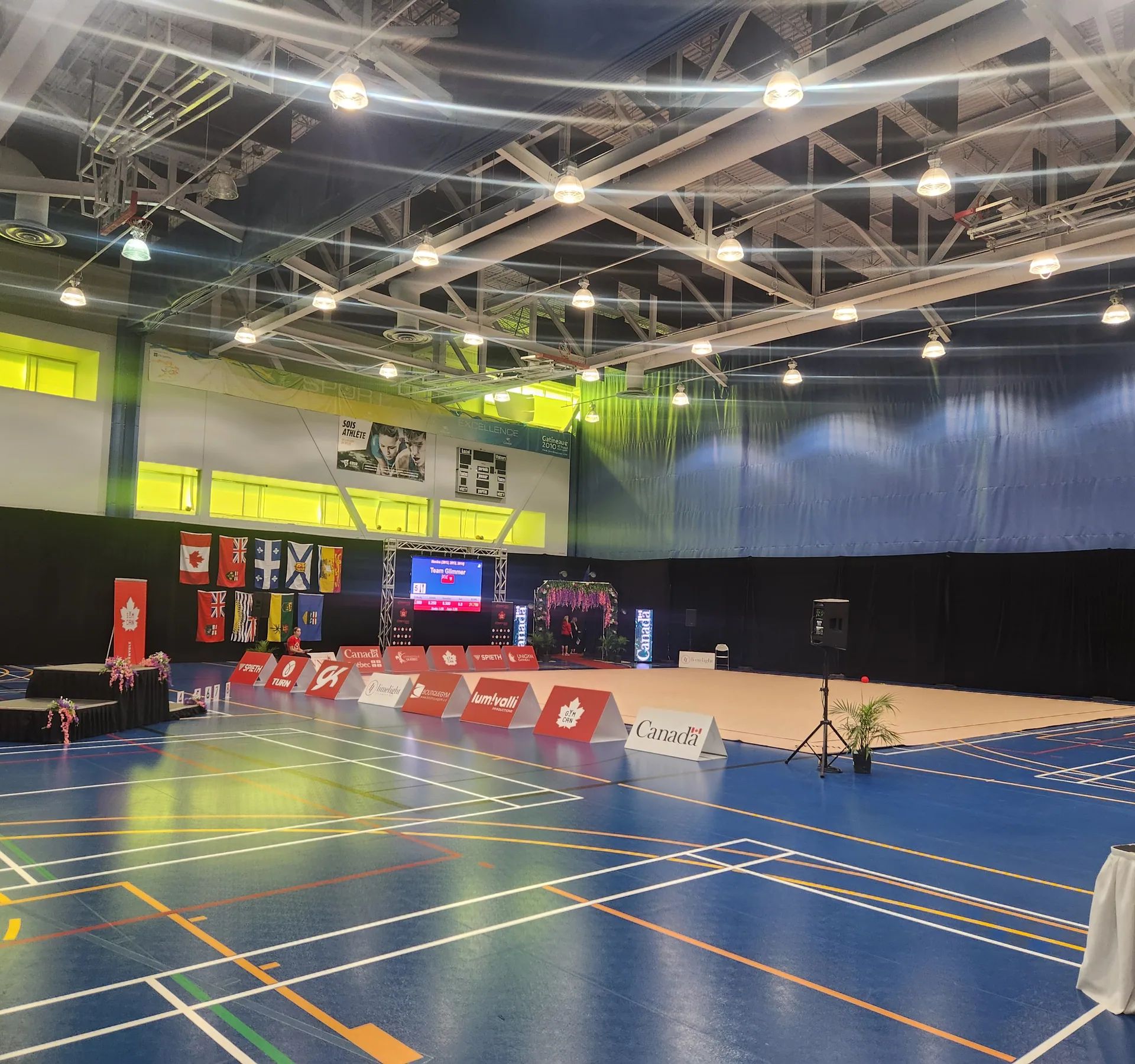 Plateau de compétition installé dans un gymnase, tables et écrans