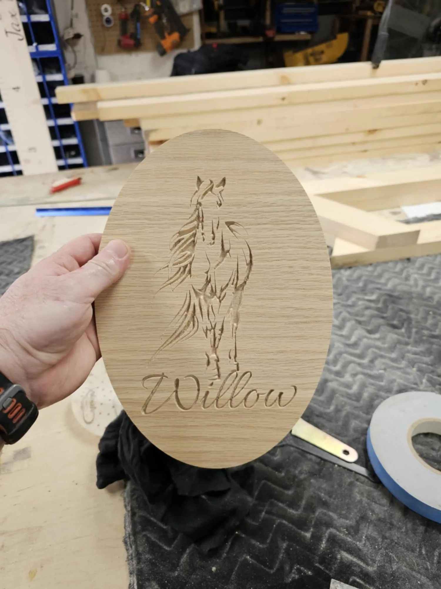 Plaque ronde en bois gravée d’un cheval, tenue en main