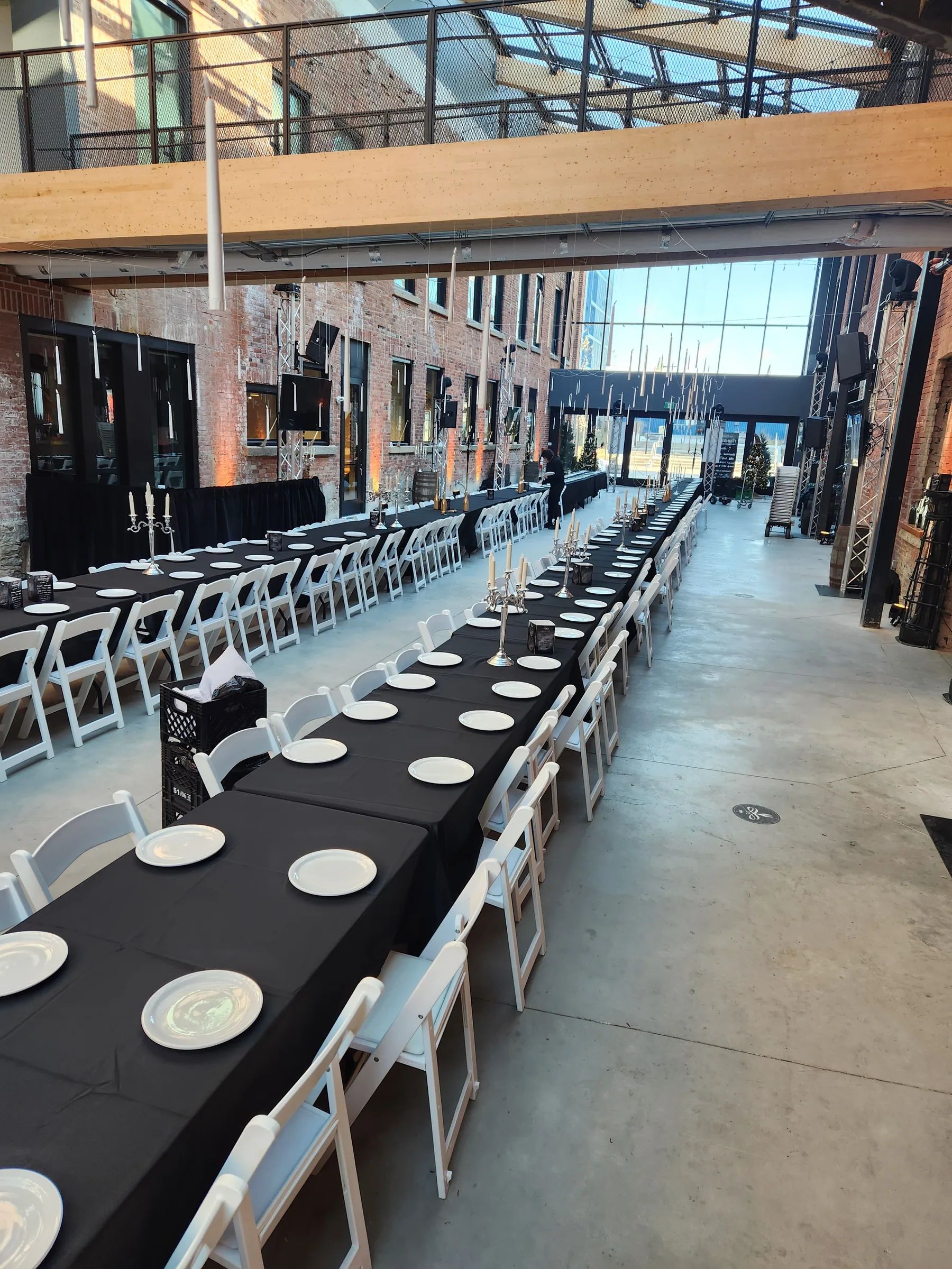Tables de banquet nappées de noir alignées sous une verrière