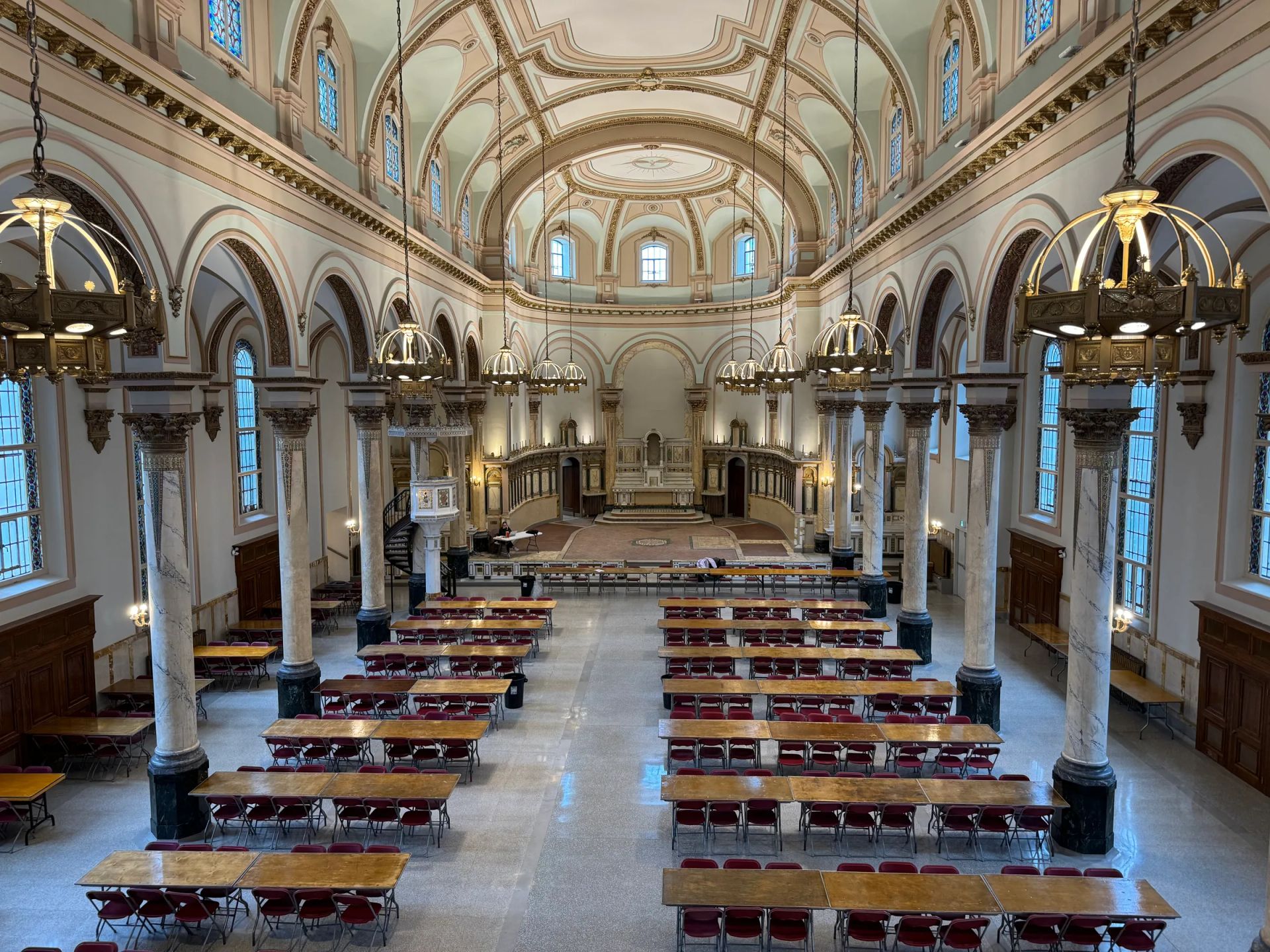 Nef d’une église aménagée en salle de réception, longues tables et lustres