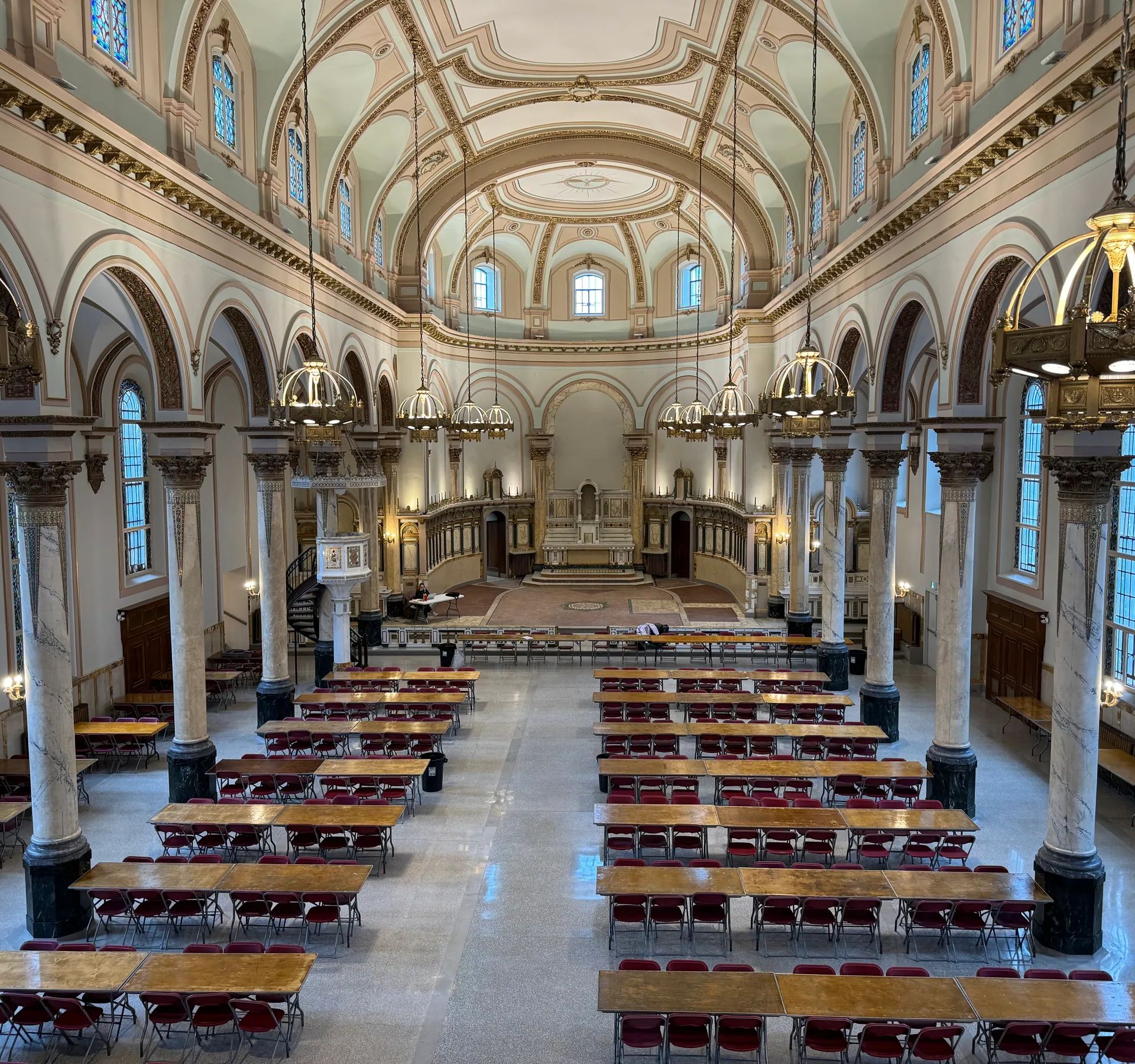 Nef d’une église aménagée en salle de réception, longues tables et lustres